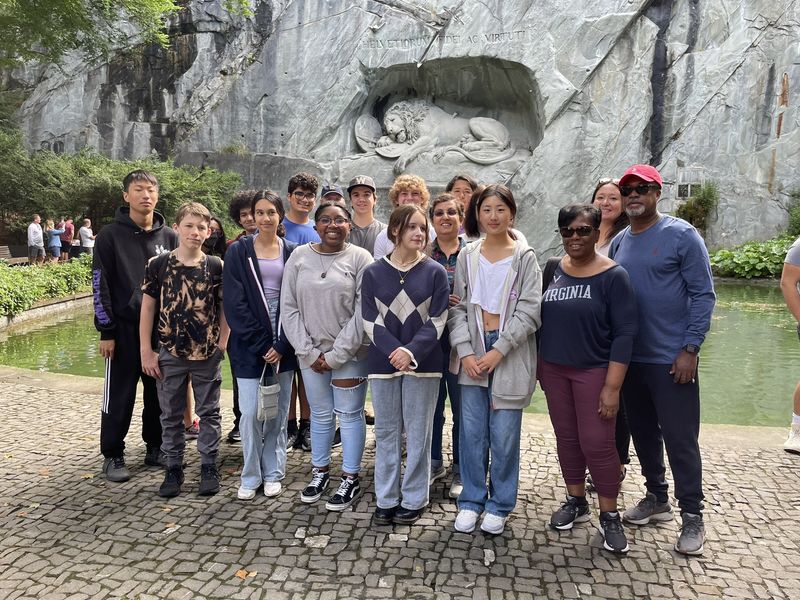 A group of people pose in front of the Lion Monument in Lucerne, Switzerland.