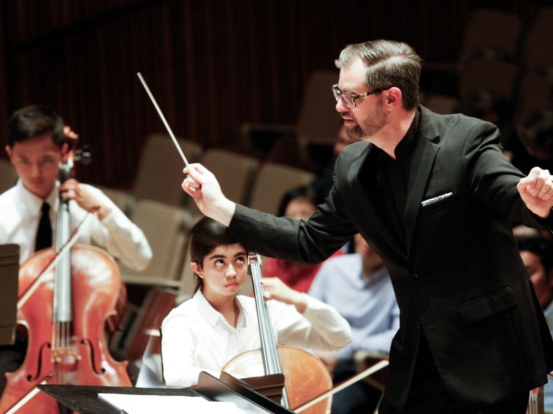 A conductor leads a youth orchestra.