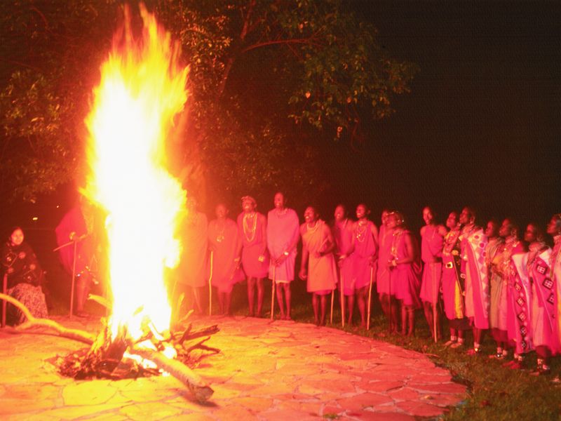 Maasai people gathered around a bonfire at night.