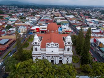 An aerial perspective of a white cathedral with a red dome, nestled in the heart of Liberia, Costa Rica.