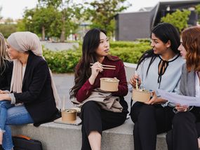 Four young adult businesswomen having lunch outdoors