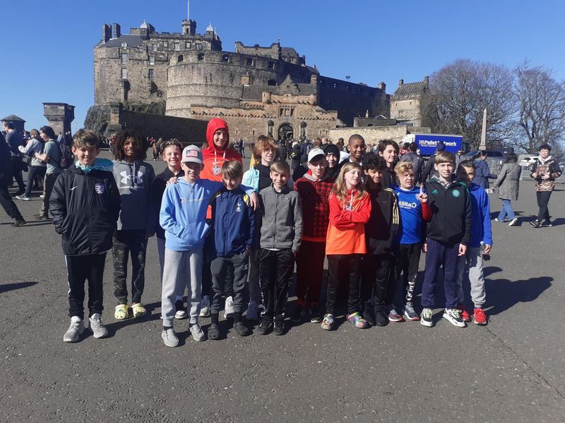 A group of children pose for a photo in front of the historic Edinburgh Castle in Scotland.