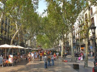 Crowds of people enjoy a sunny day walking down La Rambla in Barcelona, Spain