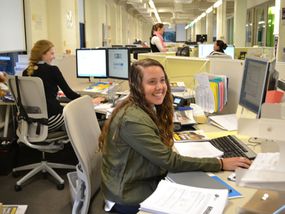 Young adult woman at desk in open plan office