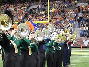 A high school marching band performing during halftime at a football game in the Alamodome.