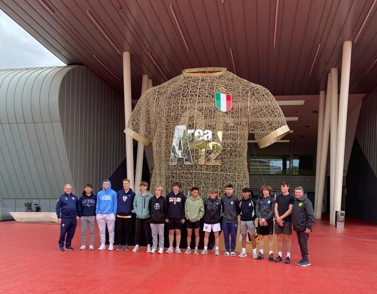 Group photo of a soccer team in front of a giant Italian national team jersey in Florence, Italy.