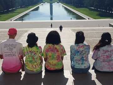 Group of teenagers at the Lincoln Memorial overlooking the reflecting pool and Washington Monument.