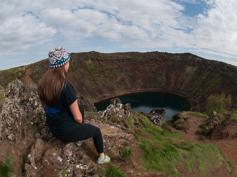 Young woman sits overlooking Kerid Crater Lake.