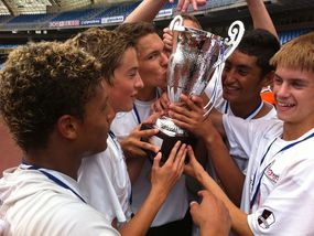 Teenage soccer team celebrating with a trophy.