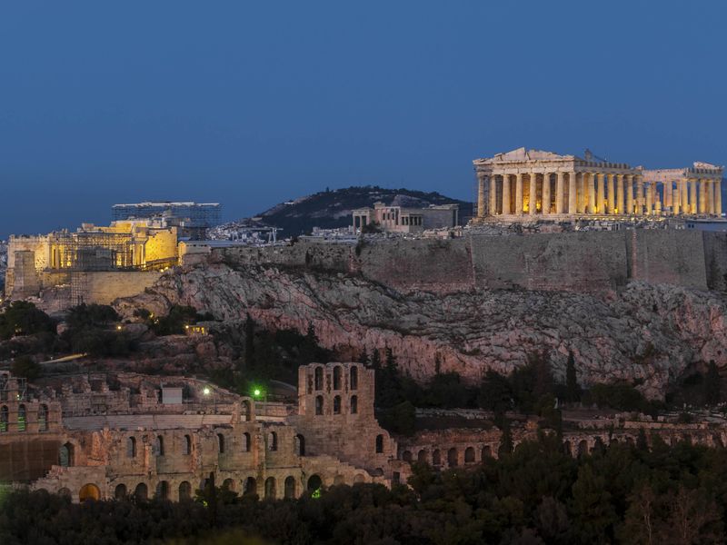 The Parthenon and Odeon of Herodes Atticus illuminated at dusk in Athens, Greece.