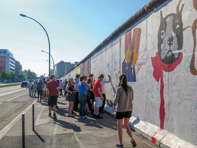 Group of young people viewing Berlin Wall art at the East Side Gallery.