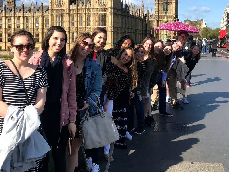 Group of young adults posing for a photo with the Houses of Parliament and Elizabeth Tower in London, UK.