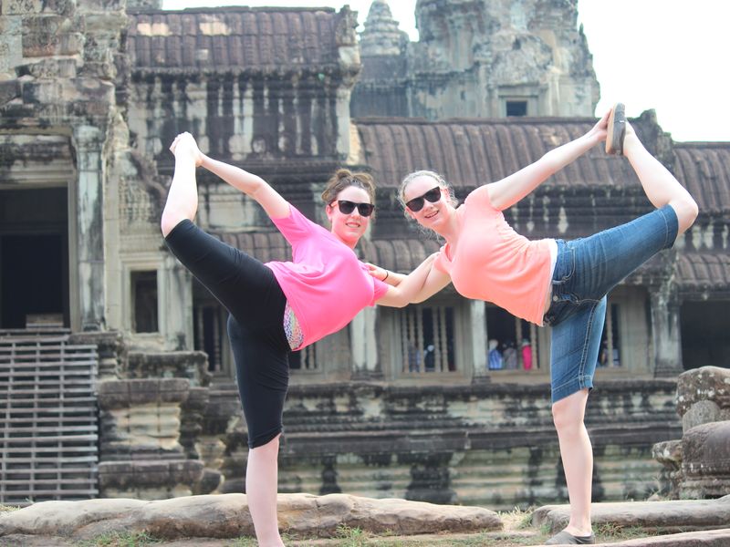 Two women practice yoga at Angkor Wat.