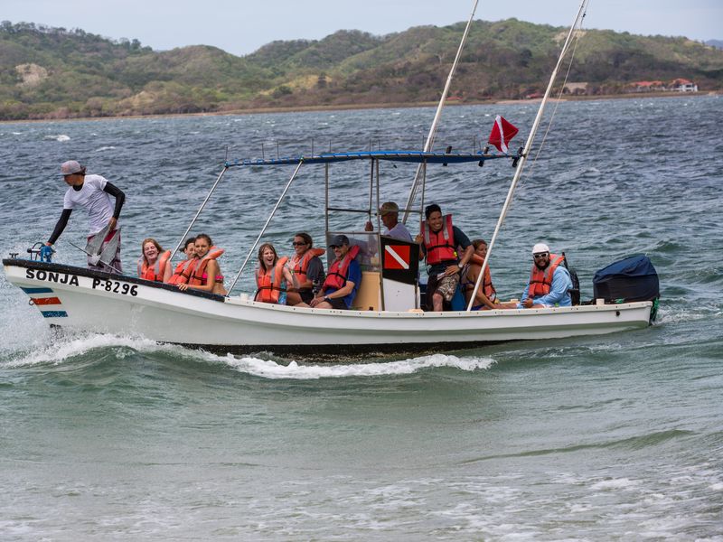 A boat filled with people rides the waves in a beautiful ocean setting.