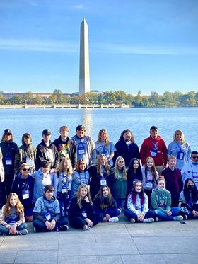 Group photo of teenagers and adults in front of the Washington Monument.