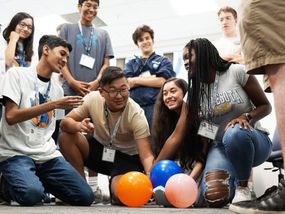 Teenagers collaborate on a balloon robot project, demonstrating teamwork and STEM skills.