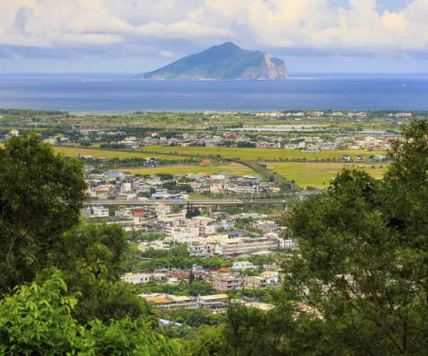 Aerial view of a coastal town in Taiwan with Guishan Island in the distance.