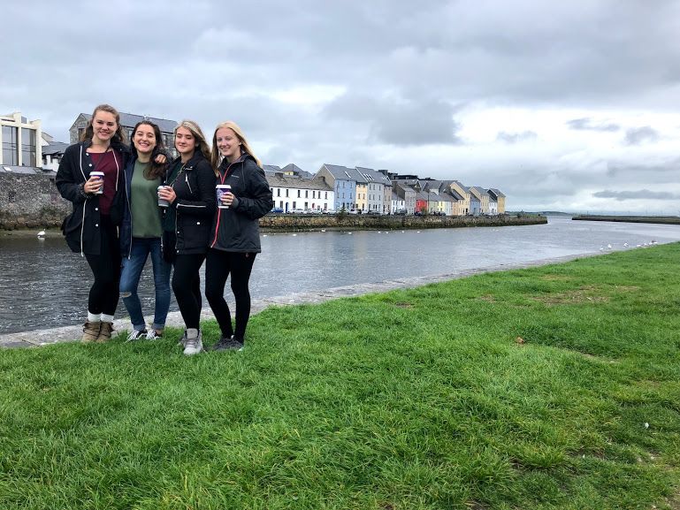 Four young adults enjoying coffee by the river in Galway, Ireland