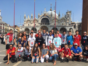 Group of young adults and teenagers in front of St. Mark's Basilica in Venice, Italy.