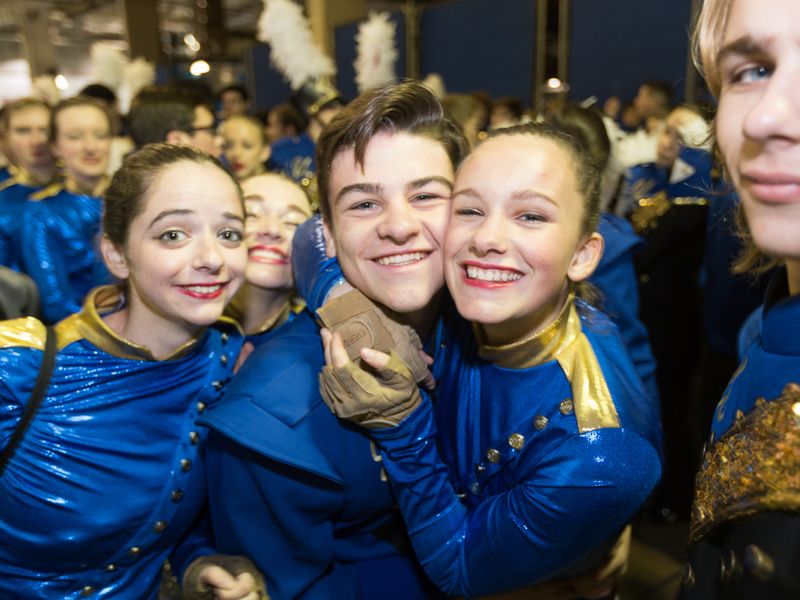 Group of teenagers in blue and gold marching band uniforms