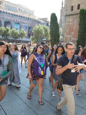 A group of teenagers on a guided walking tour of a historical site in Barcelona.