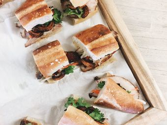 Several Vietnamese banh mi sandwiches arranged on a wooden tray.