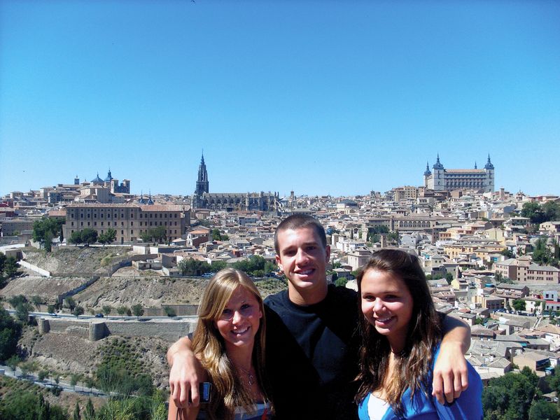 Three friends pose for a photo overlooking the cityscape of Toledo, Spain.