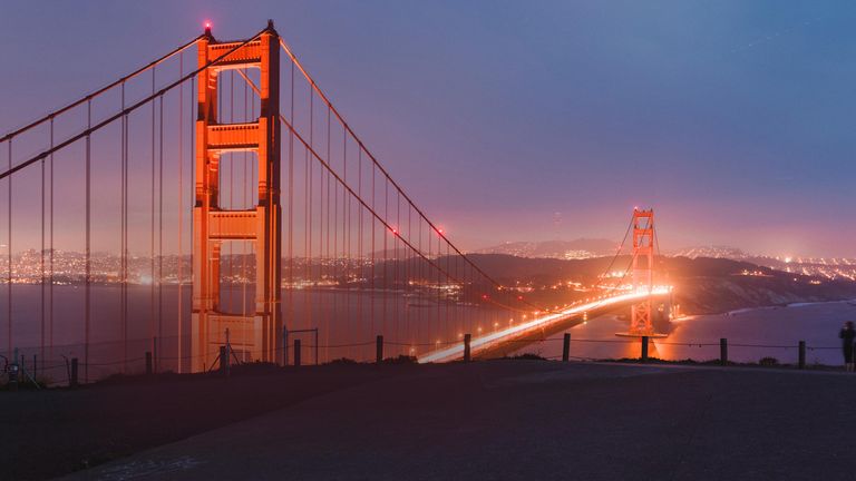 night view of the bright orange golden gate bridge with bright lights