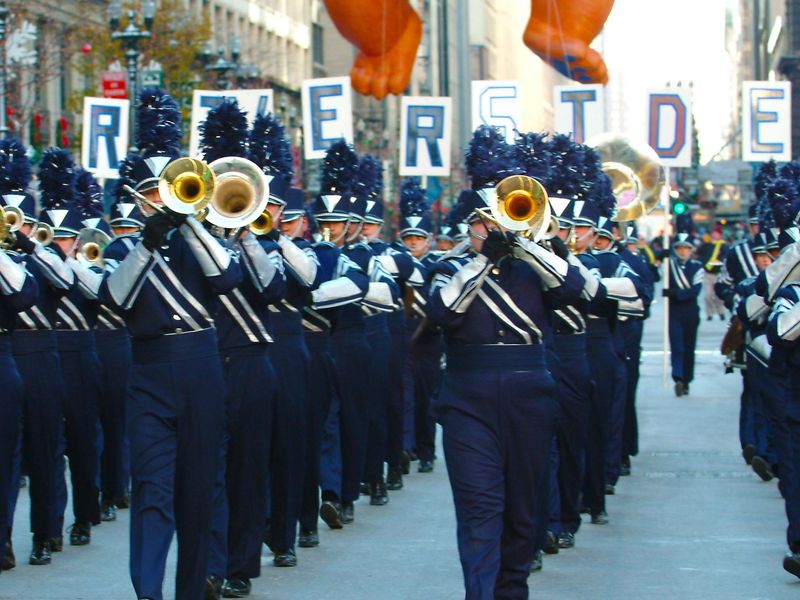 A marching band in blue and white uniforms performs in a parade.