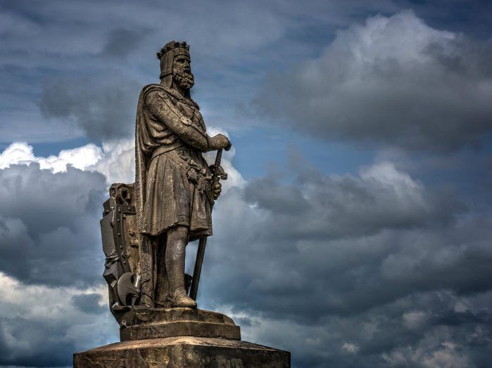 A majestic statue of William Wallace against a backdrop of a cloudy sky.