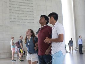 Three teenagers looking up at an inscription inside the Jefferson Memorial.