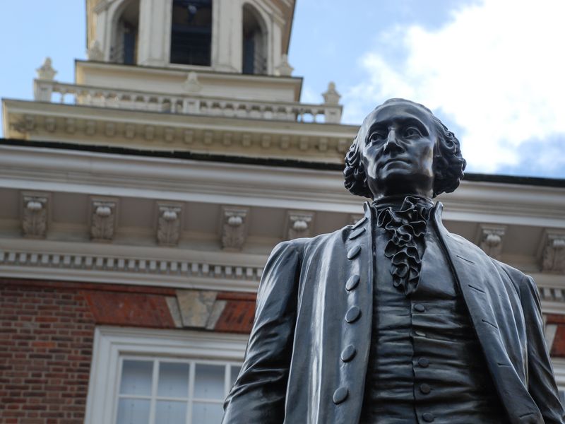 Bronze statue of a historical figure in front of a historic red brick building.