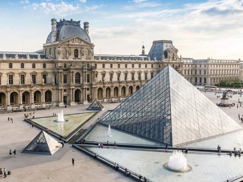 The Louvre Museum in Paris, France with the glass pyramid in the foreground.