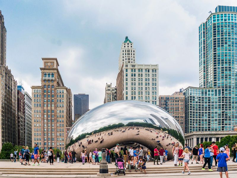 Cloud Gate sculpture in Chicago's Millennium Park reflects the city skyline and the people walking around it