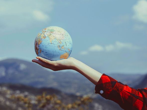 A woman holding a globe in her hand, symbolizing travel and adventure.