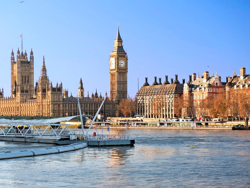 The Palace of Westminster and Big Ben Clock Tower stand majestically beside the River Thames in London, England.