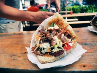 A gyro sandwich on a white paper plate.