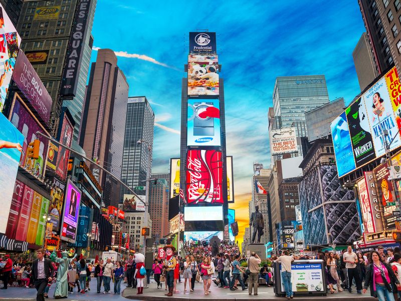 A vibrant evening scene in Times Square, New York City, with crowds of people and illuminated billboards creating a dynamic and energetic atmosphere.