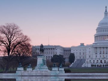 The US Capitol building at dawn reflected in the Capitol Reflecting Pool.