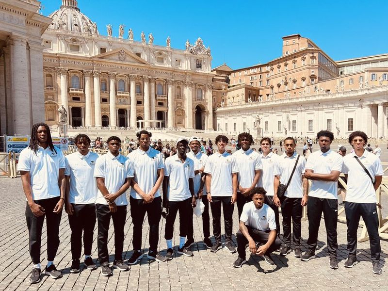 Group of young adults standing in front of St. Peter's Basilica in Vatican City.