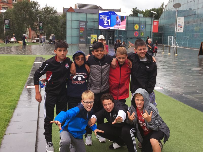 Group of children and teenagers posing outside the National Football Museum.