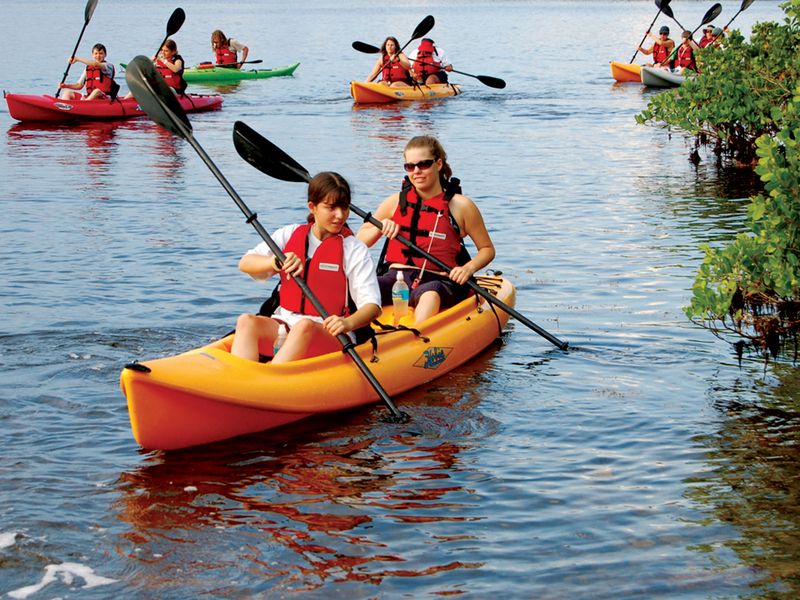 Two people kayaking on a orange kayak with a group