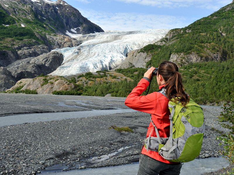 Woman looking at a glacier through binoculars