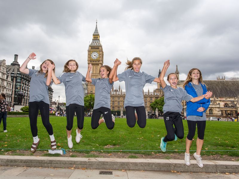 Group of teenage girls jumping in front of Elizabeth Tower