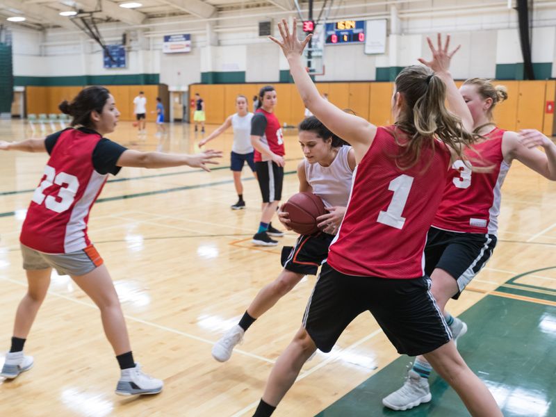 Young adult women playing basketball in a gymnasium