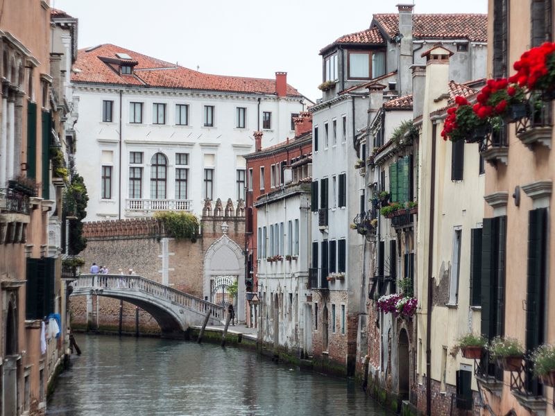 A canal scene in Venice with a bridge and colorful buildings.