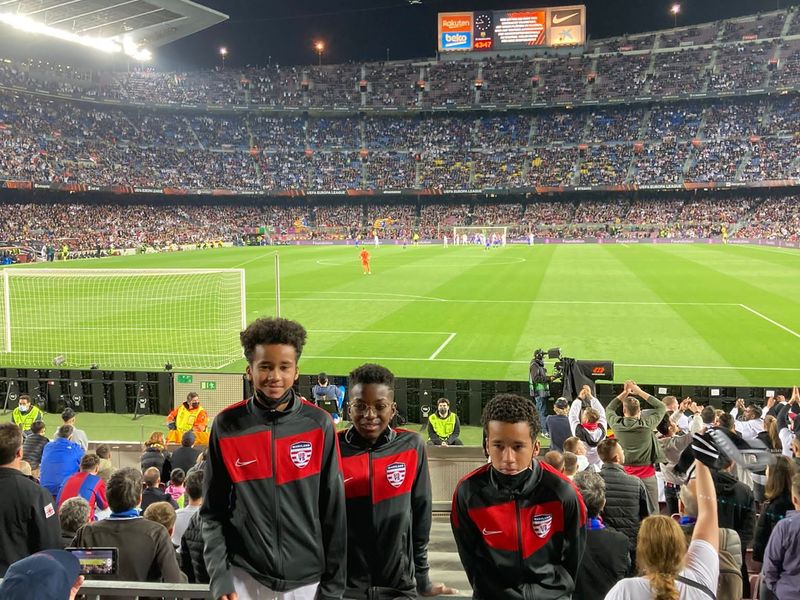 Three children at a soccer game in a packed stadium