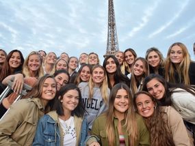 Group of young women posing for a photo with the Eiffel Tower in the background