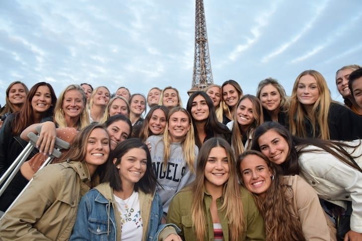 Group of young women posing for a photo with the Eiffel Tower in the background