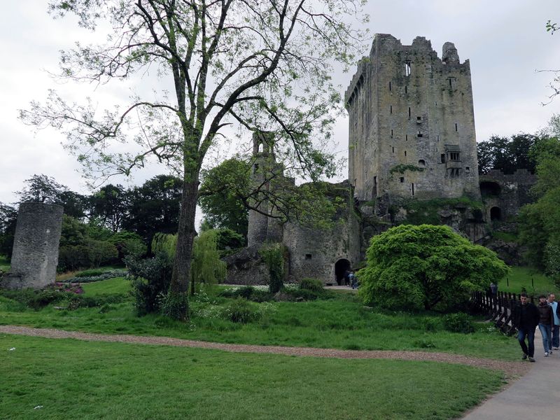 Blarney Castle, Ireland, a historic stone castle with lush green grounds and a cloudy sky.